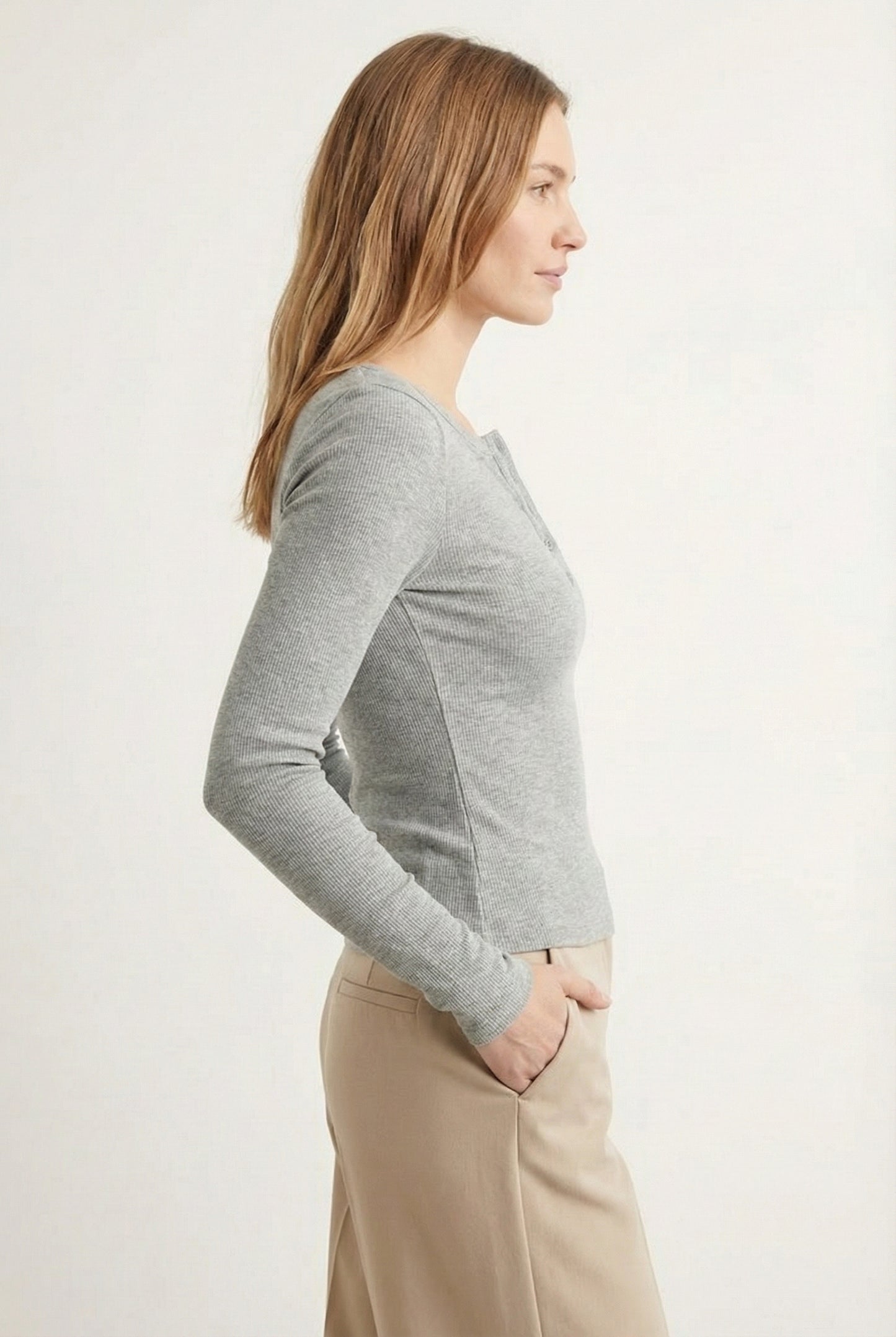 Woman wearing the LOHNR Haven Henley in Cement, a light grey ribbed long-sleeve top with a button placket, styled for effortless everyday luxury.