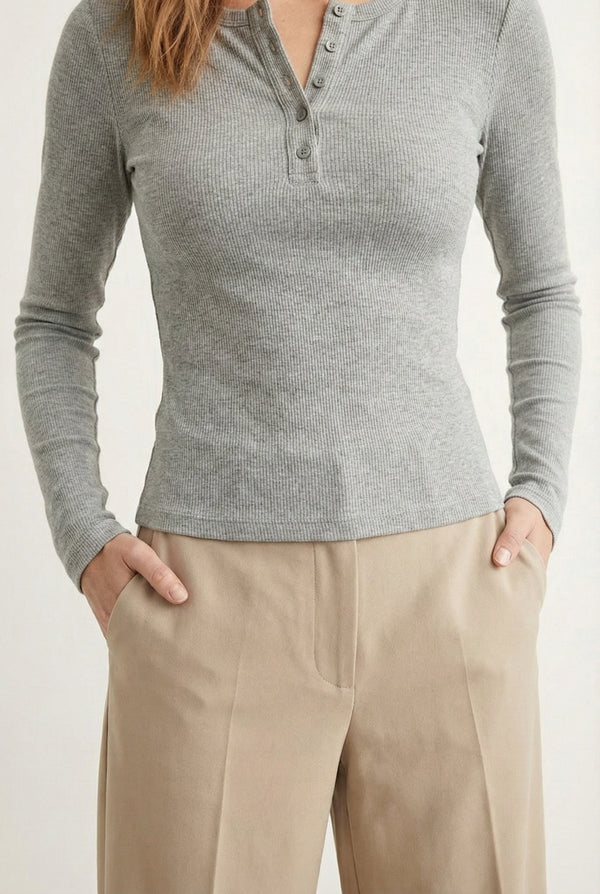 Woman wearing the LOHNR Haven Henley in Cement, a light grey ribbed long-sleeve top with a button placket, styled for effortless everyday luxury.