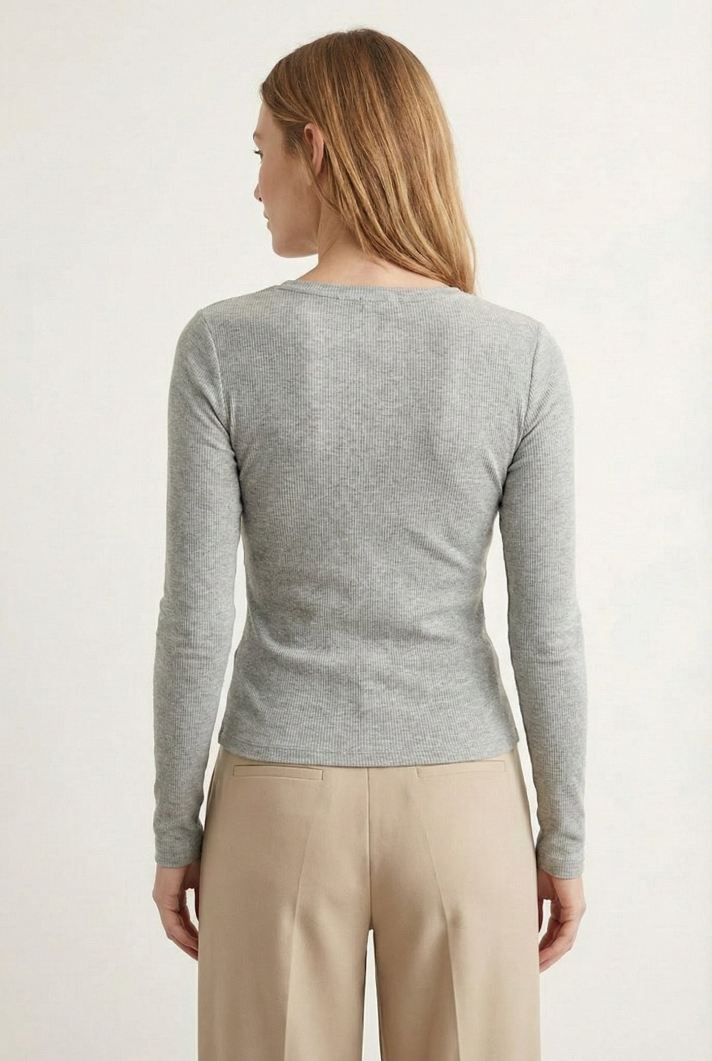 Woman wearing the LOHNR Haven Henley in Cement, a light grey ribbed long-sleeve top with a button placket, styled for effortless everyday luxury.