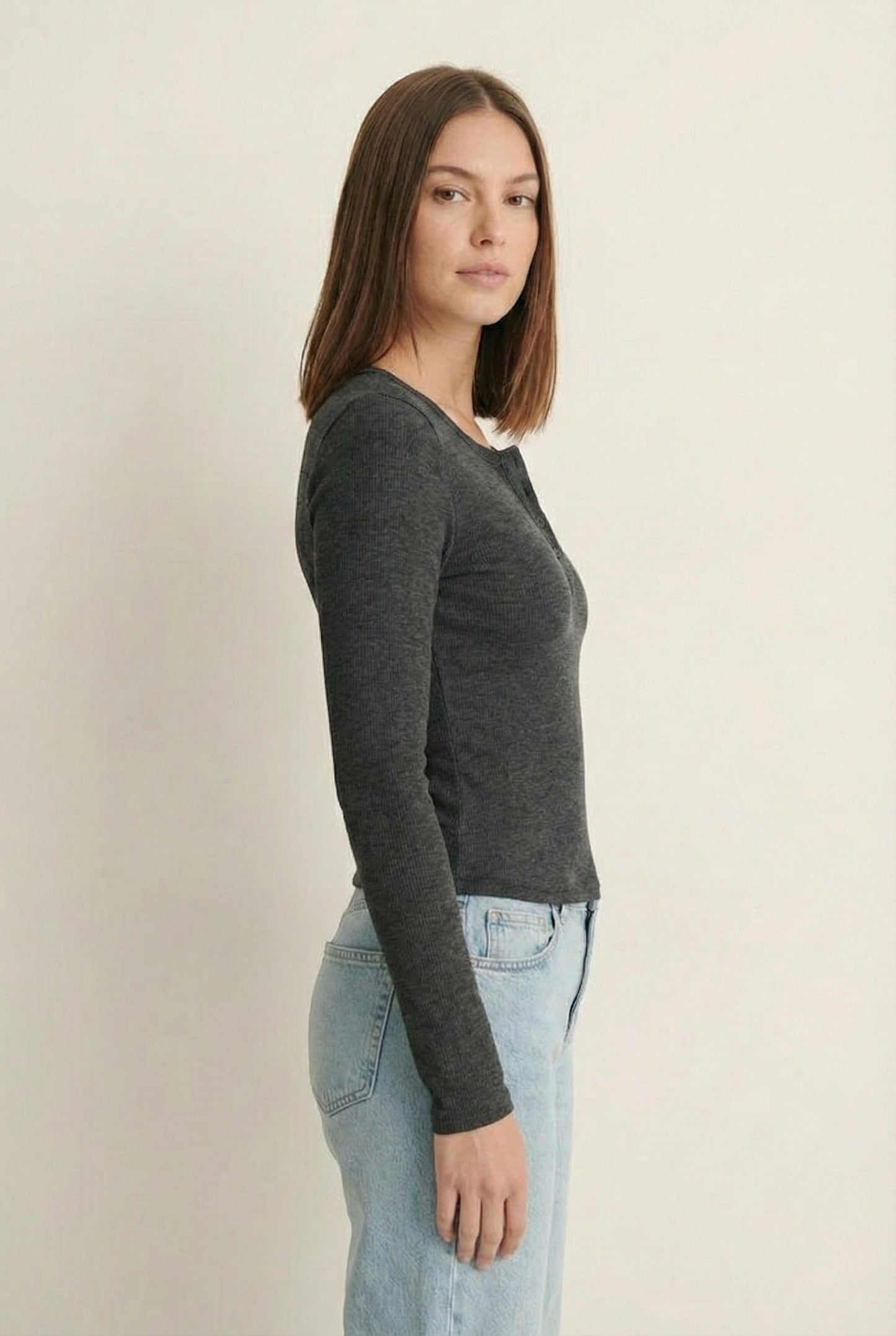 Woman wearing the LOHNR Haven Henley in Heather Charcoal, a dark grey ribbed long-sleeve top with a button placket, styled for effortless everyday luxury.
