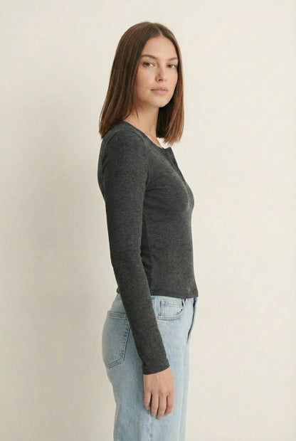 Woman wearing the LOHNR Haven Henley in Heather Charcoal, a dark grey ribbed long-sleeve top with a button placket, styled for effortless everyday luxury.