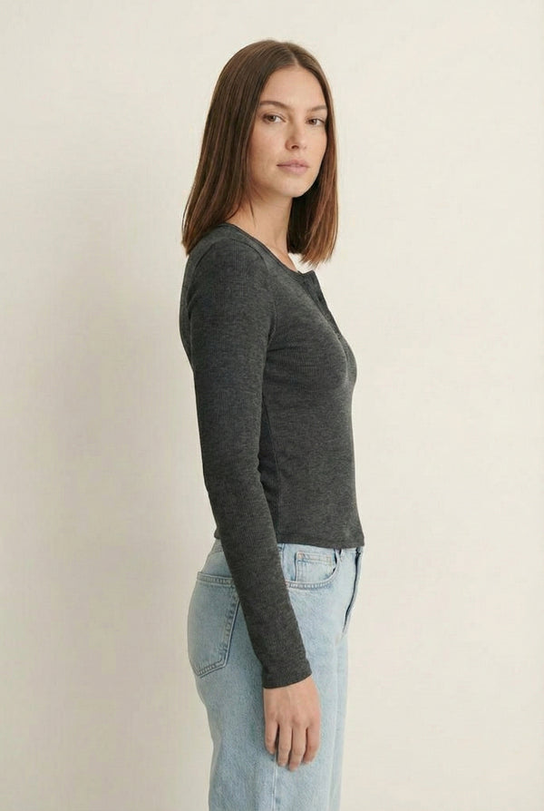 Woman wearing the LOHNR Haven Henley in Heather Charcoal, a dark grey ribbed long-sleeve top with a button placket, styled for effortless everyday luxury.