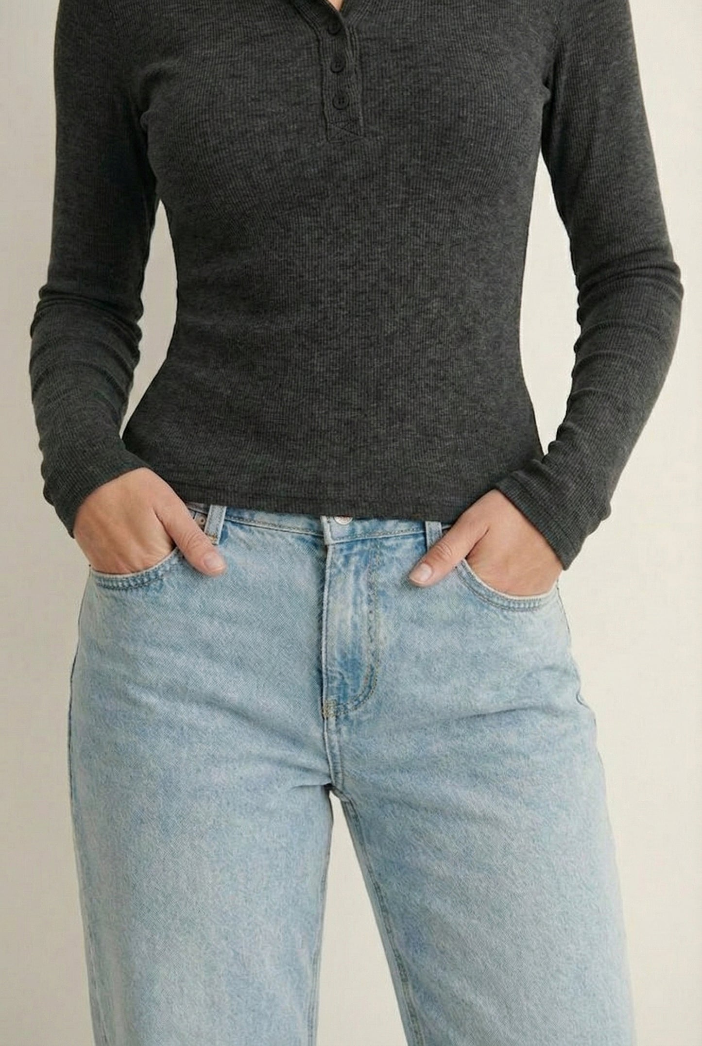 Woman wearing the LOHNR Haven Henley in Heather Charcoal, a dark grey ribbed long-sleeve top with a button placket, styled for effortless everyday luxury.