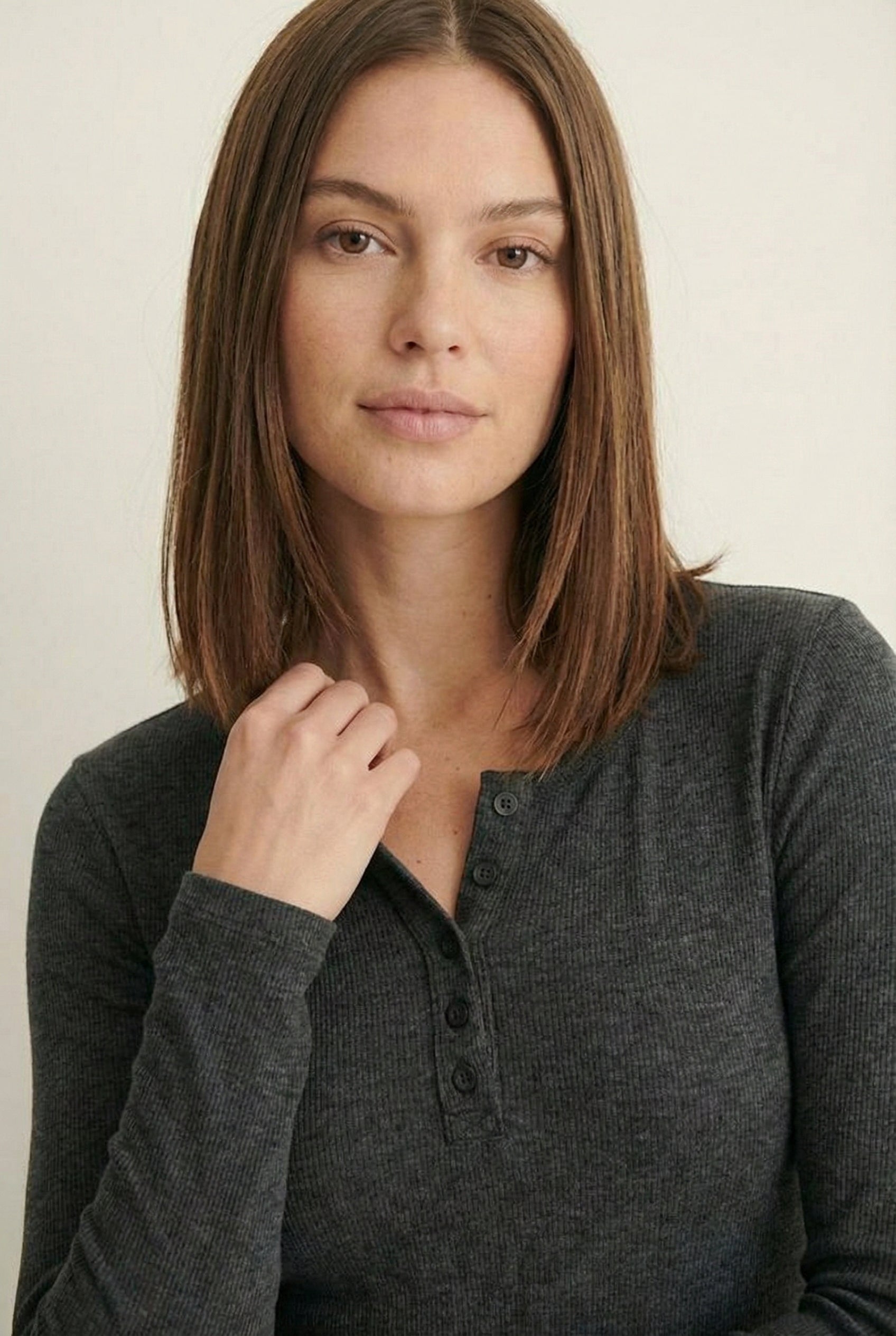 Woman wearing the LOHNR Haven Henley in Heather Charcoal, a dark grey ribbed long-sleeve top with a button placket, styled for effortless everyday luxury.