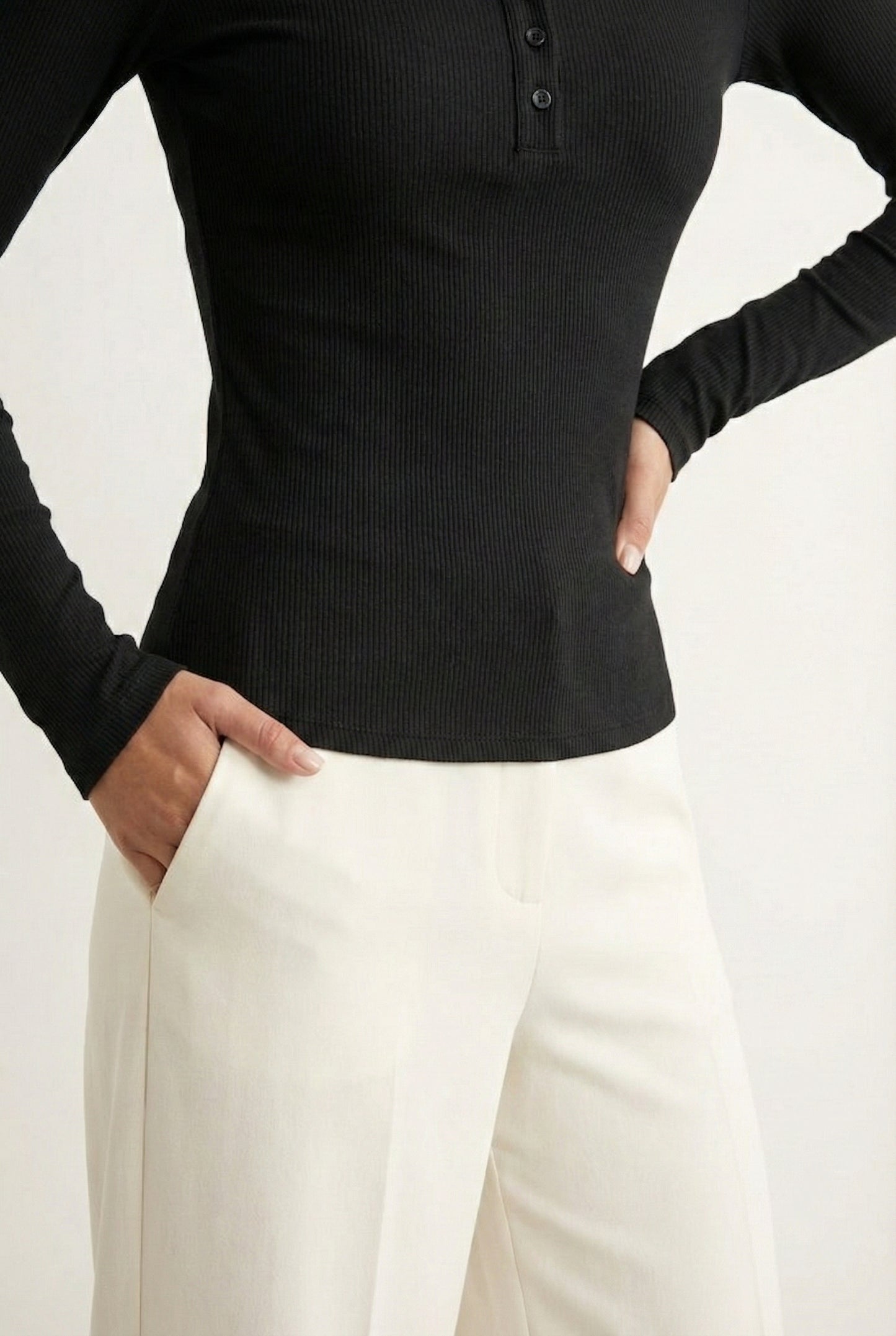 Woman wearing the LOHNR Haven Henley in Rich Black, a sleek black ribbed long-sleeve top with a button placket, styled for effortless everyday luxury.