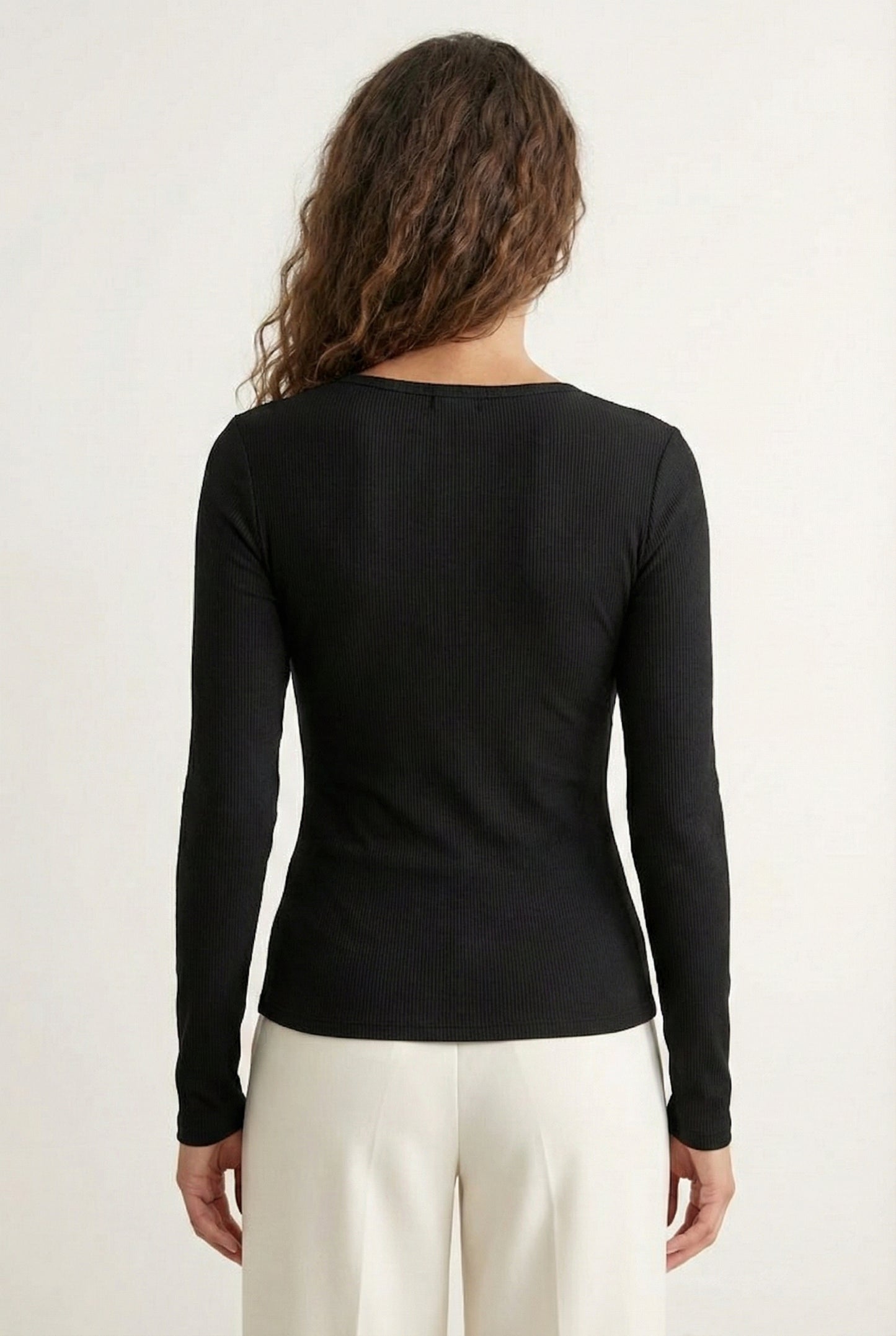 Woman wearing the LOHNR Haven Henley in Rich Black, a sleek black ribbed long-sleeve top with a button placket, styled for effortless everyday luxury.