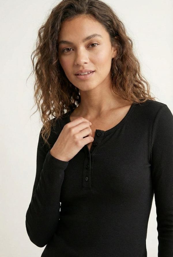 Woman wearing the LOHNR Haven Henley in Rich Black, a sleek black ribbed long-sleeve top with a button placket, styled for effortless everyday luxury.