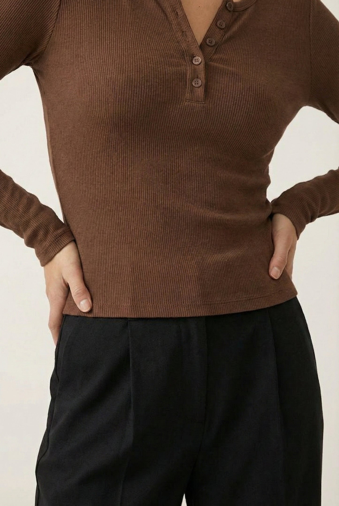 Woman wearing the LOHNR Haven Henley in Truffle, a rich brown ribbed long-sleeve top with a button placket, styled for effortless everyday luxury.
