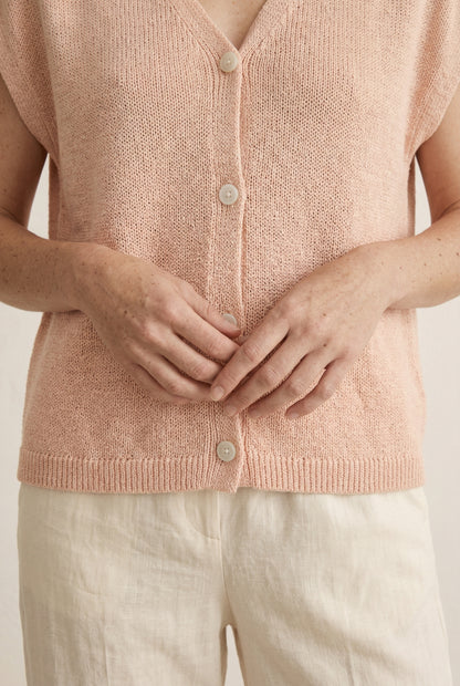Woman modeling the LOHNR short sleeve v-neck knit top in washed apricot featuring a button-down front.