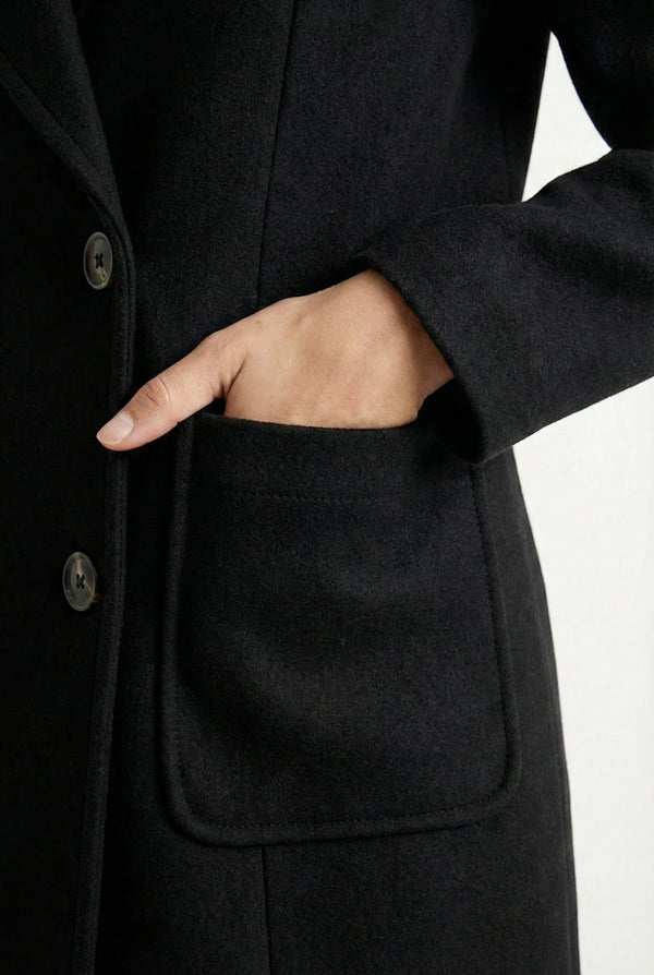 Onyx black Mercer Coat by LOHNR, a tailored faux wool trench coat featuring structured lapels, deep utility pockets, and a refined quiet luxury aesthetic.