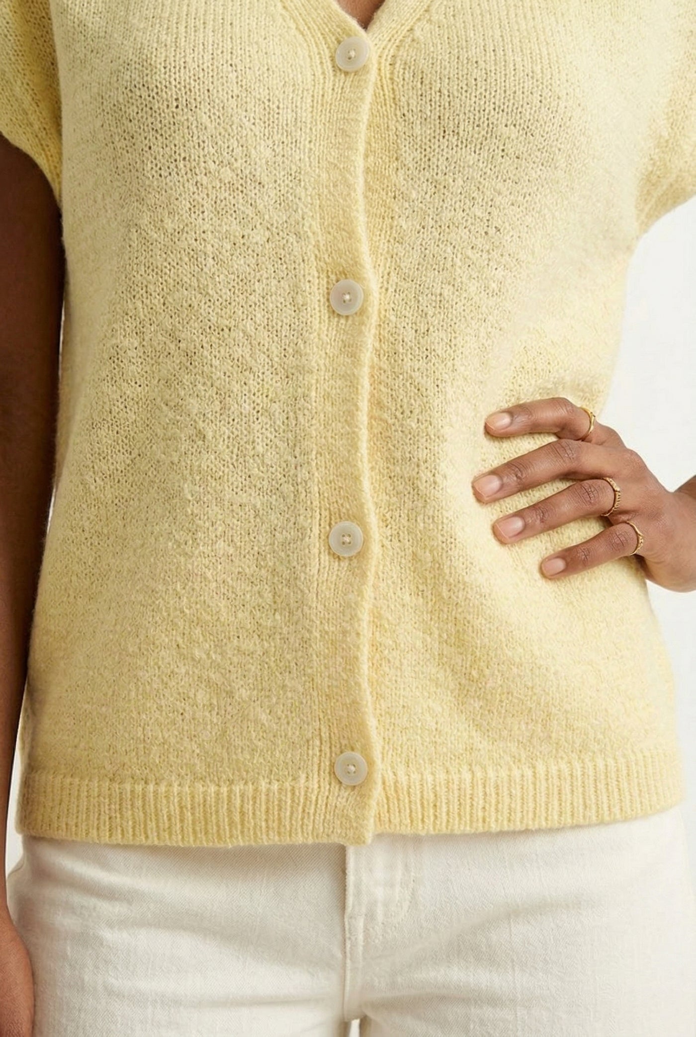 Woman modeling the LOHNR short sleeve v-neck knit top in pale yellow Meringue featuring a button-down front.