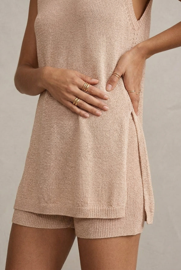 A woman wearing the LOHNR Slouch Tunic Set in Glossy Sand, a neutral beige sleeveless knit loungewear set.