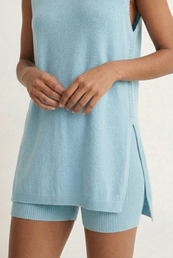 A woman wearing the LOHNR Slouch Tunic Set in Iced Sky, a soft pale blue sleeveless tunic and shorts set.