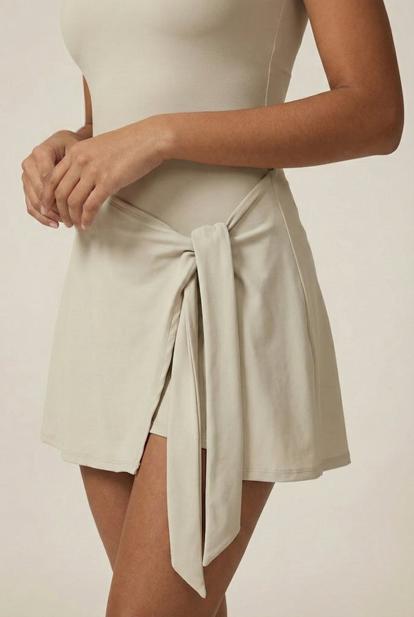 LOHNR The Rally Dress in Beige - Athletic one-piece romper with side-tie wrap skirt and hidden integrated shorts