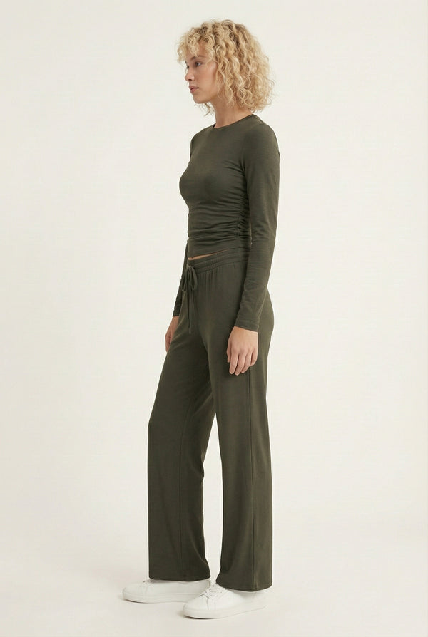 Model wearing The Rive Set sleek stretch lounge set in Cypress by Lohnr, featuring a ruched long-sleeve top and wide-leg drawstring pants