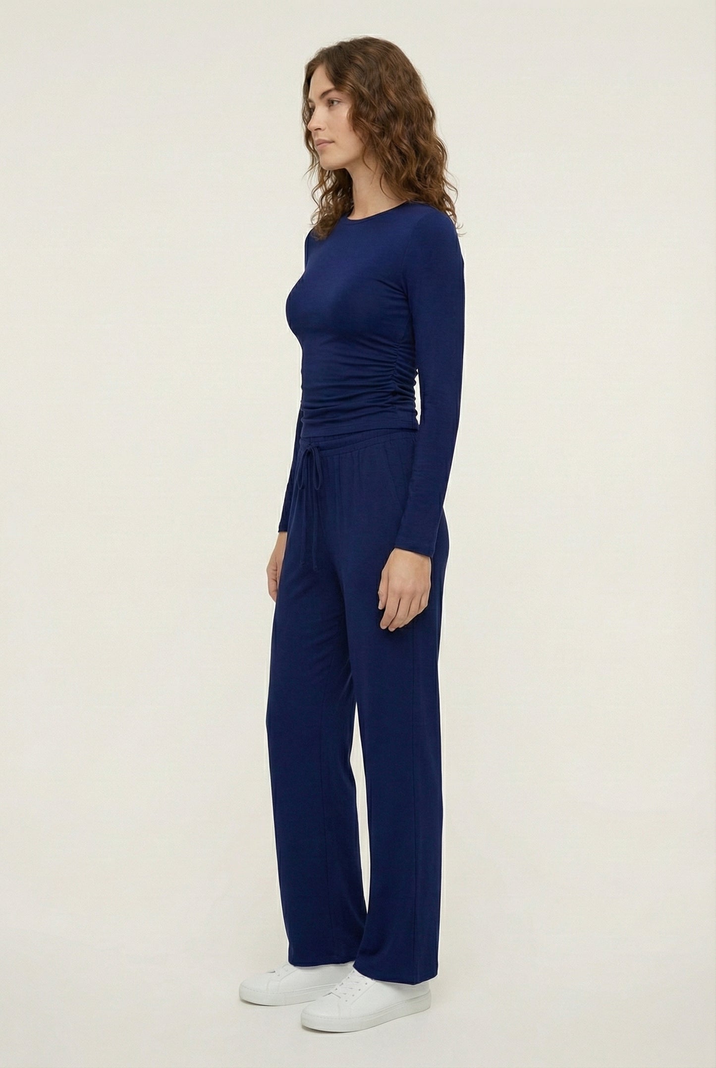 Model wearing The Rive Set sleek stretch lounge set in Indigo by Lohnr, featuring a ruched long-sleeve top and wide-leg drawstring pants