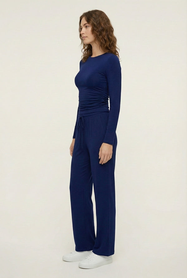 Model wearing The Rive Set sleek stretch lounge set in Indigo by Lohnr, featuring a ruched long-sleeve top and wide-leg drawstring pants