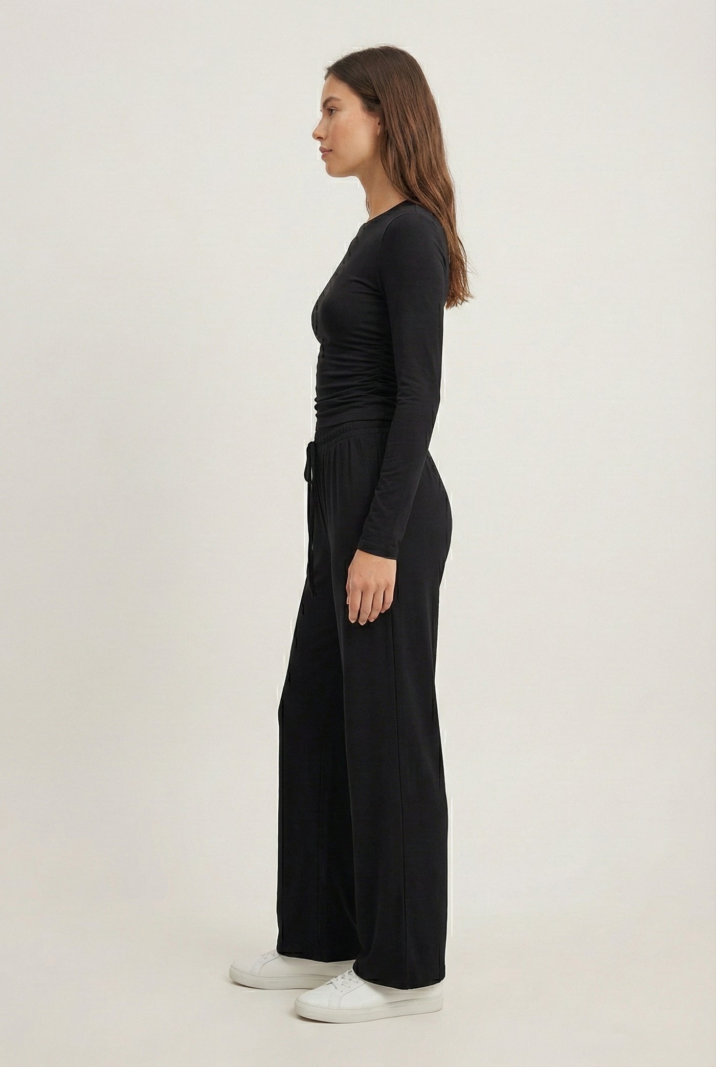 Model wearing The Rive Set sleek stretch lounge set in Noir by Lohnr, featuring a ruched long-sleeve top and wide-leg drawstring pants