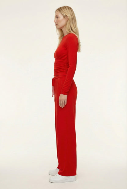 Model wearing The Rive Set sleek stretch lounge set in Rouge by Lohnr, featuring a ruched long-sleeve top and wide-leg drawstring pants