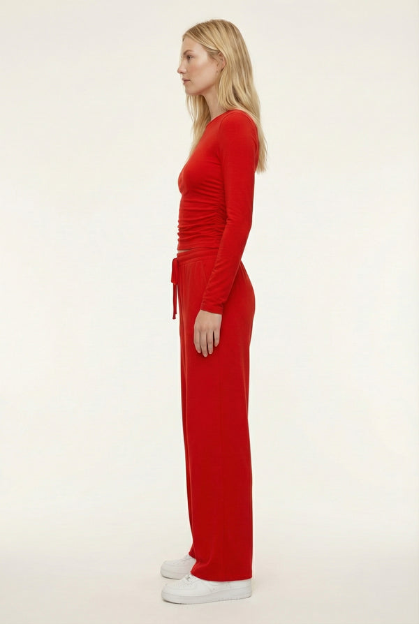 Model wearing The Rive Set sleek stretch lounge set in Rouge by Lohnr, featuring a ruched long-sleeve top and wide-leg drawstring pants