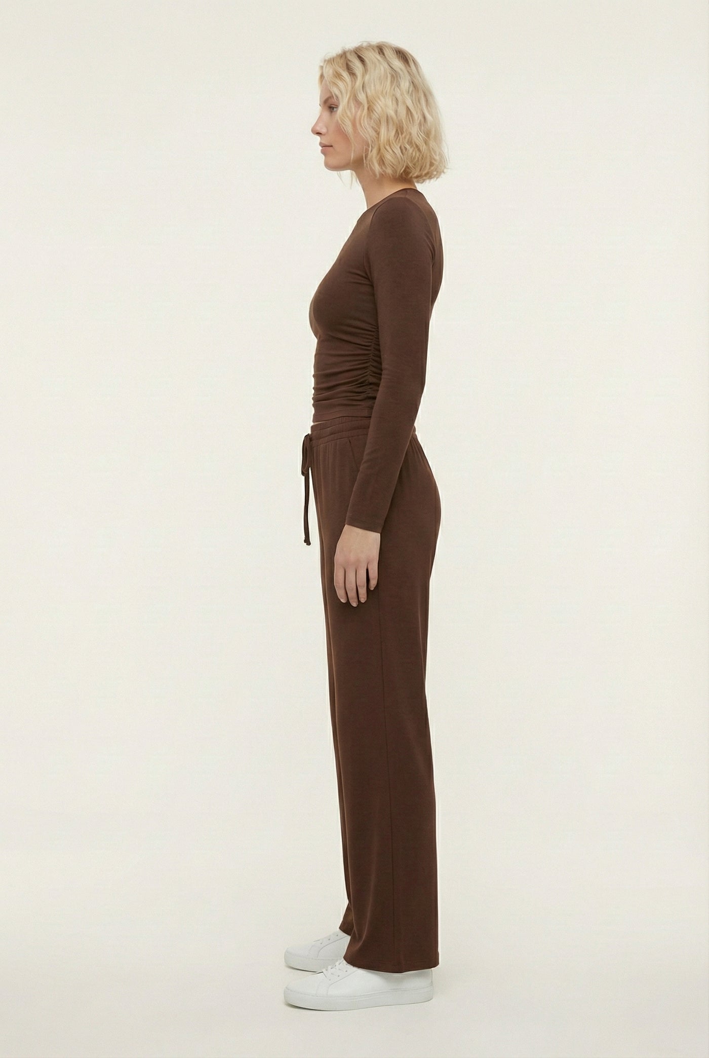 Model wearing The Rive Set sleek stretch lounge set in Truffle by Lohnr, featuring a ruched long-sleeve top and wide-leg drawstring pants