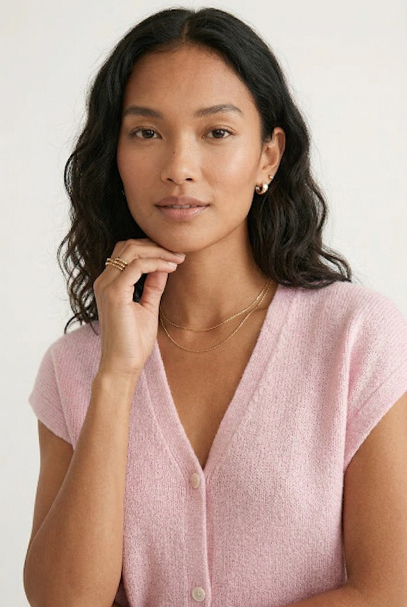 Woman modeling the LOHNR short sleeve v-neck knit top in light pink Ashen Rose featuring a button-down front.