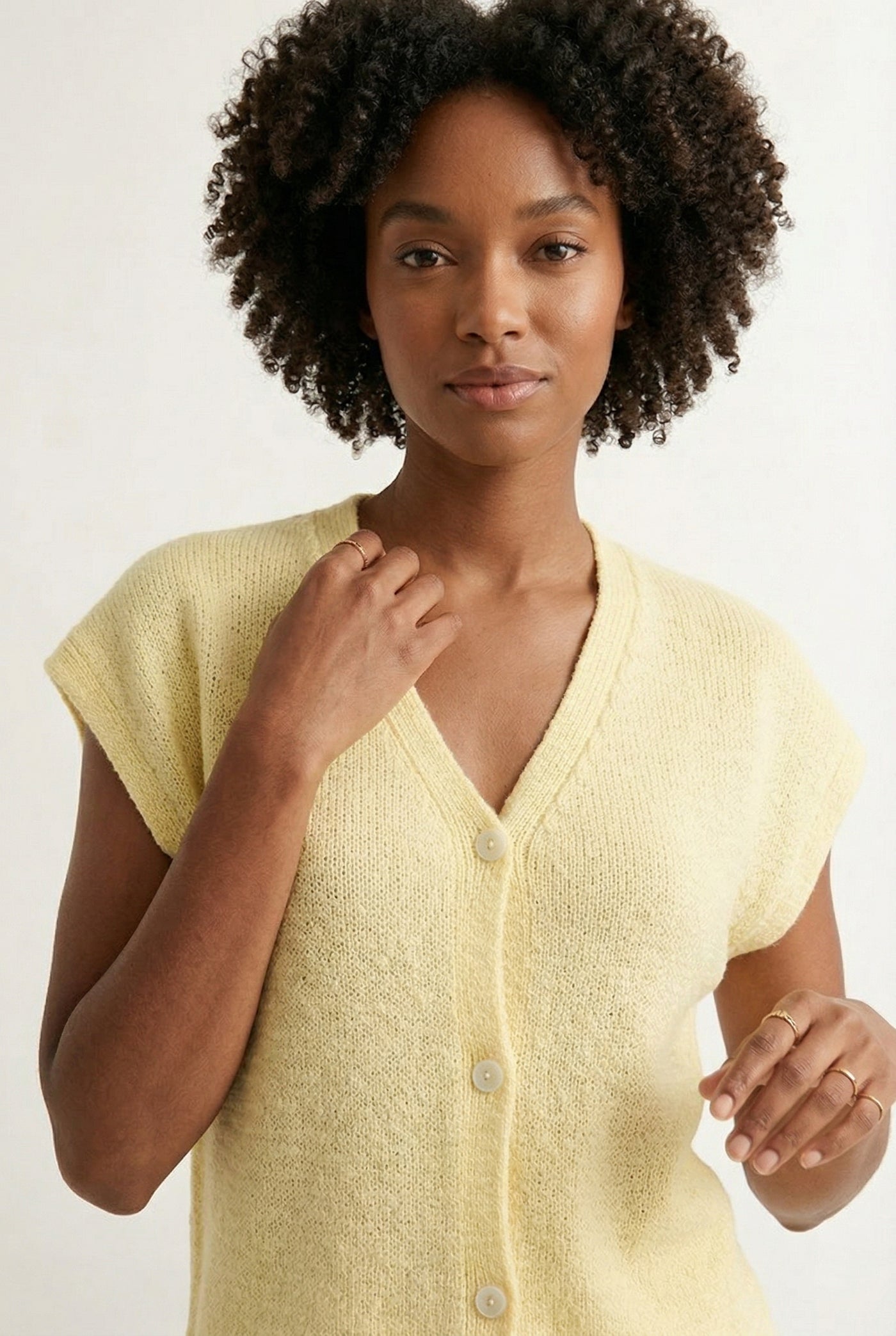 Woman modeling the LOHNR short sleeve v-neck knit top in pale yellow Meringue featuring a button-down front.