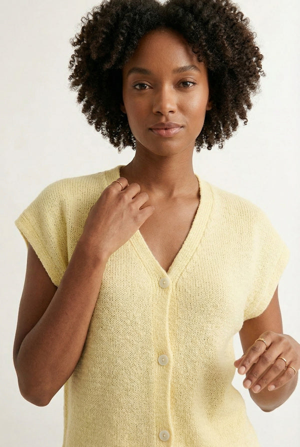 Woman modeling the LOHNR short sleeve v-neck knit top in pale yellow Meringue featuring a button-down front.