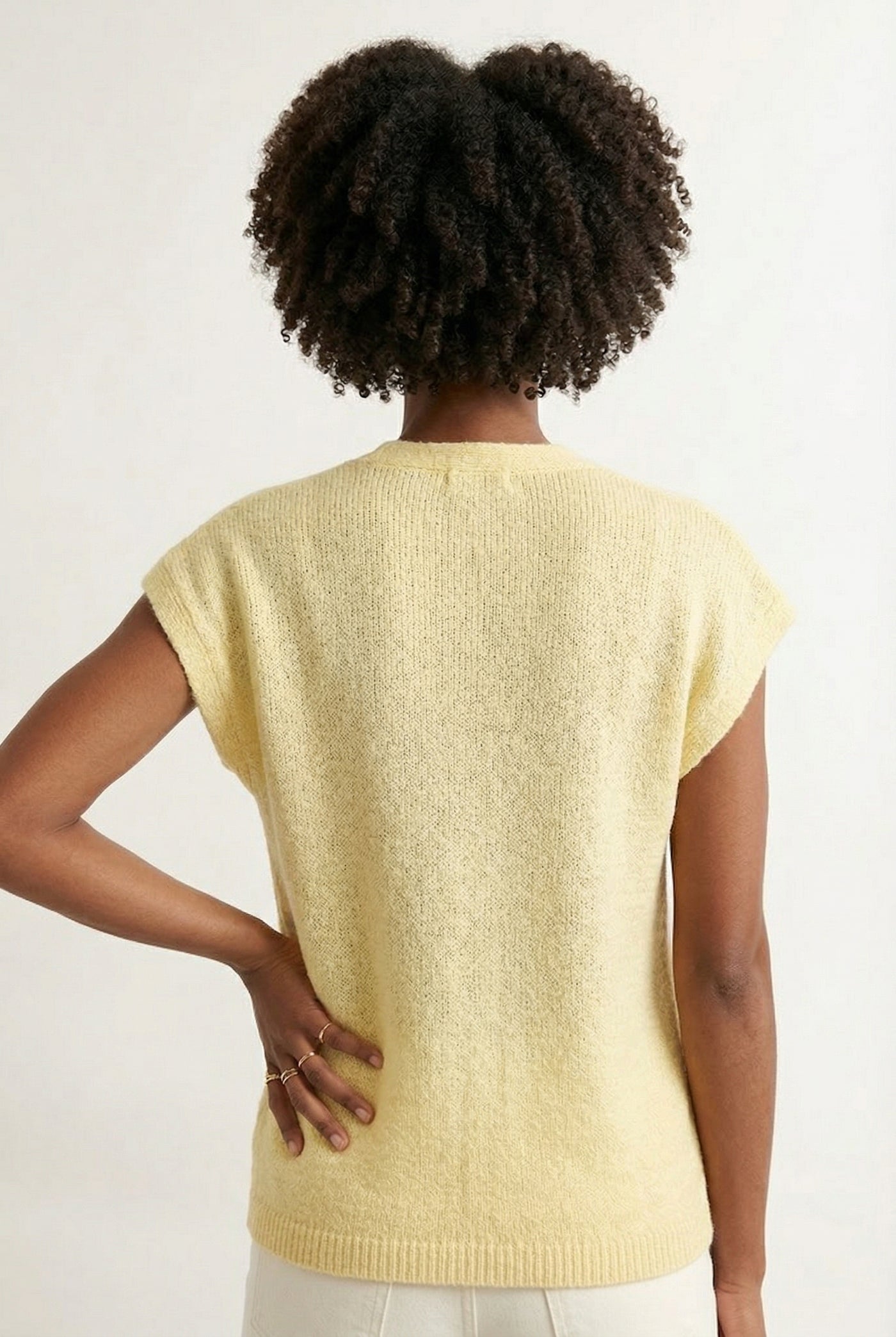 Woman modeling the LOHNR short sleeve v-neck knit top in pale yellow Meringue featuring a button-down front.