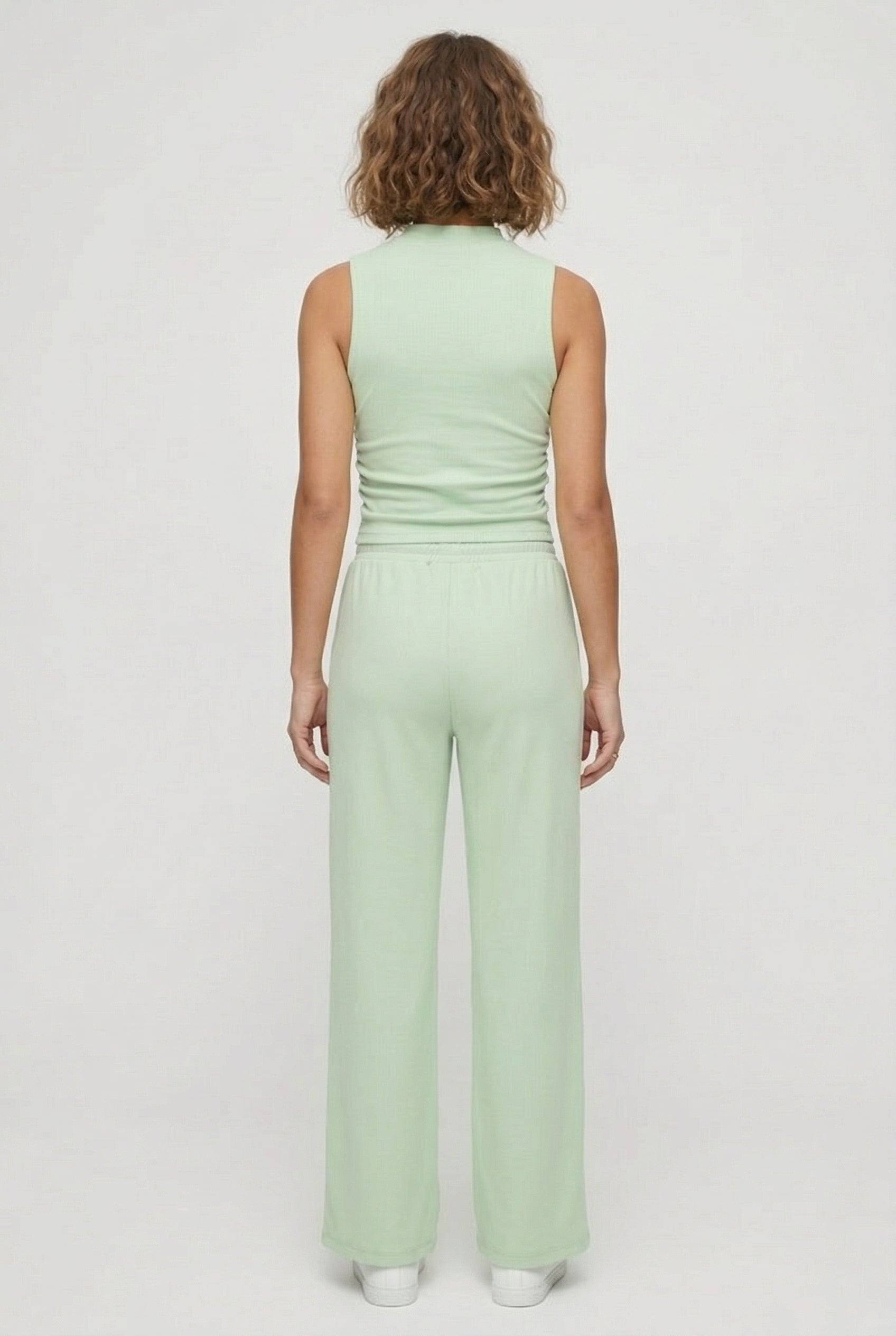 A user interface snippet from an e-commerce platform displaying a product variant row. It shows an unchecked checkbox, a thumbnail image of a model wearing a light green sleeveless jumpsuit, and the text "Sprout" above "5 variants" with a downward-pointing dropdown arrow.
