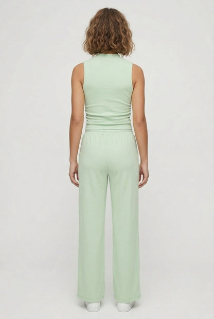 A user interface snippet from an e-commerce platform displaying a product variant row. It shows an unchecked checkbox, a thumbnail image of a model wearing a light green sleeveless jumpsuit, and the text "Sprout" above "5 variants" with a downward-pointing dropdown arrow.