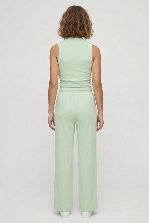 A user interface snippet from an e-commerce platform displaying a product variant row. It shows an unchecked checkbox, a thumbnail image of a model wearing a light green sleeveless jumpsuit, and the text "Sprout" above "5 variants" with a downward-pointing dropdown arrow.