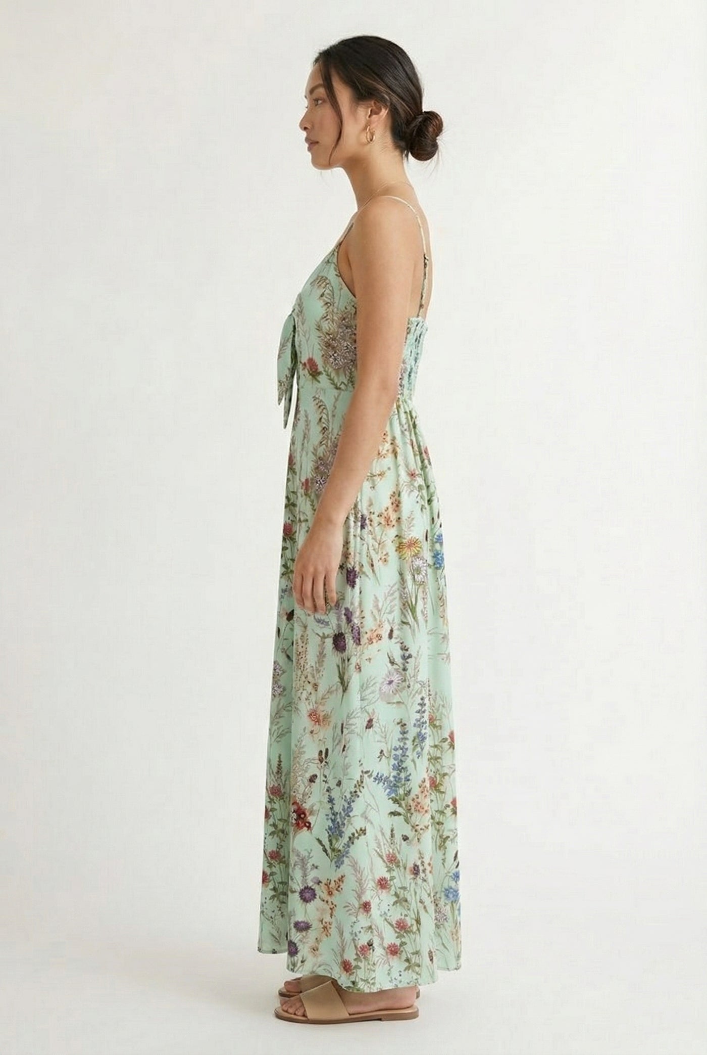 Woman wearing a matcha green floral print maxi dress with spaghetti straps