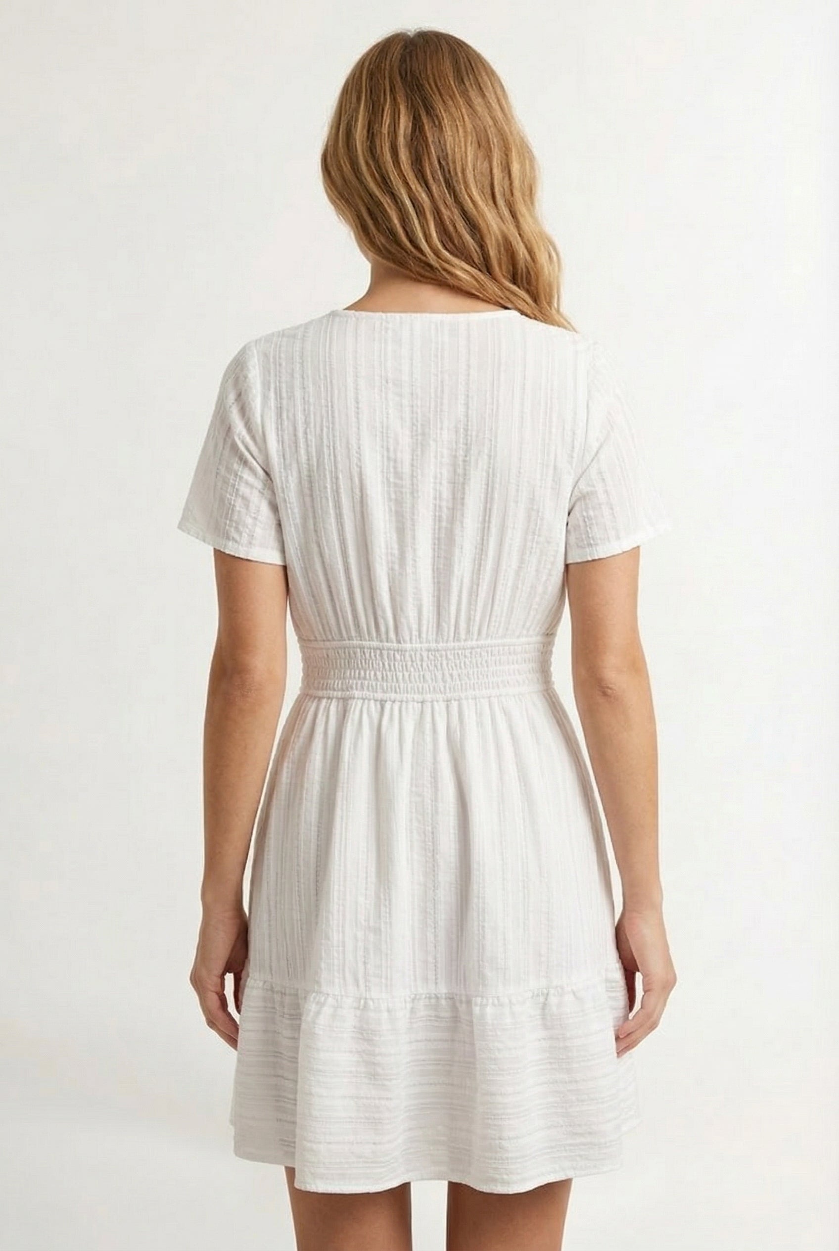 Woman wearing a short sleeve v-neck tiered dress in matte pearl white