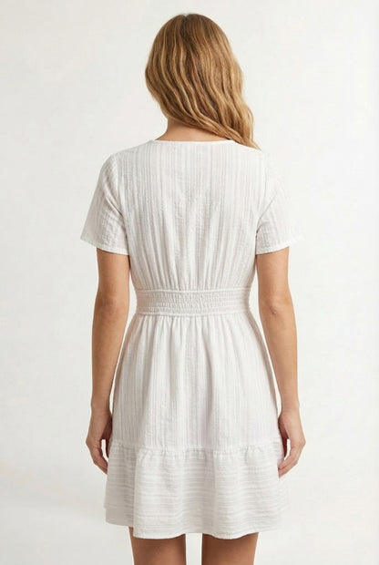 Woman wearing a short sleeve v-neck tiered dress in matte pearl white
