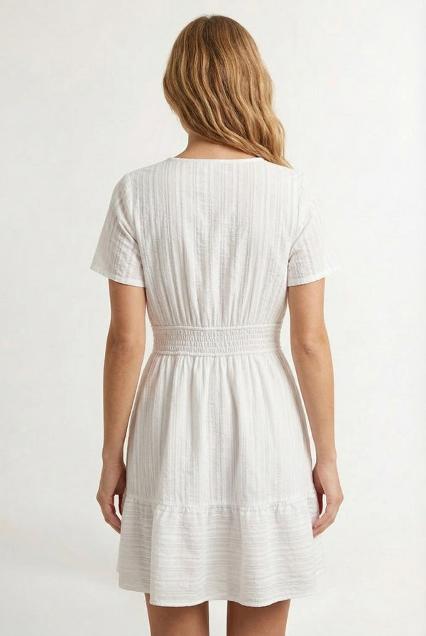 Woman wearing a short sleeve v-neck tiered dress in matte pearl white