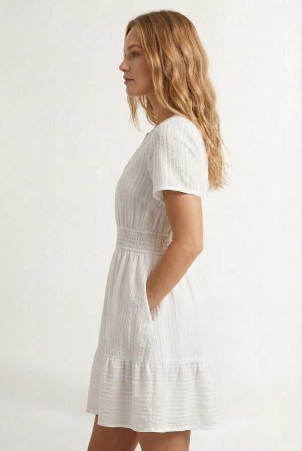 Woman wearing a short sleeve v-neck tiered dress in matte pearl white