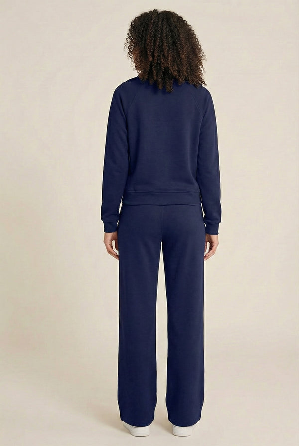 Woman wearing the LOHNR Élan Set in Midnight Navy, featuring a smooth, sweatshirt-material half-zip pullover and matching structured pants.