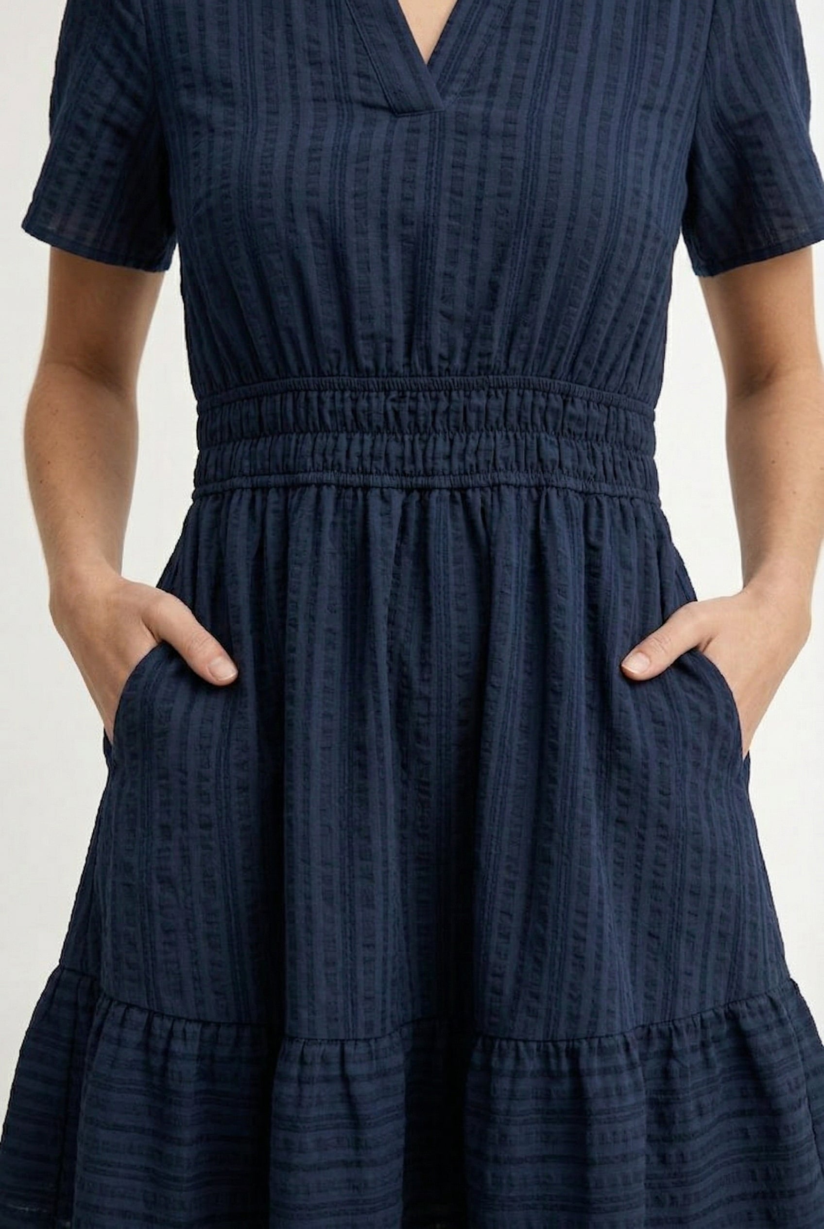 Woman wearing a short sleeve v-neck tiered dress in total eclipse navy blue