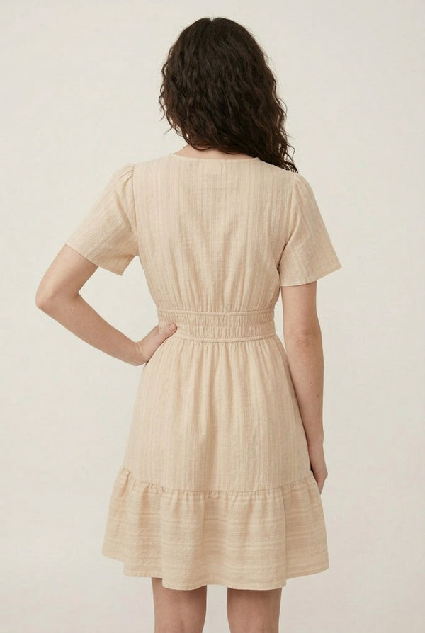 Woman wearing a short sleeve v-neck tiered dress in oat beige color