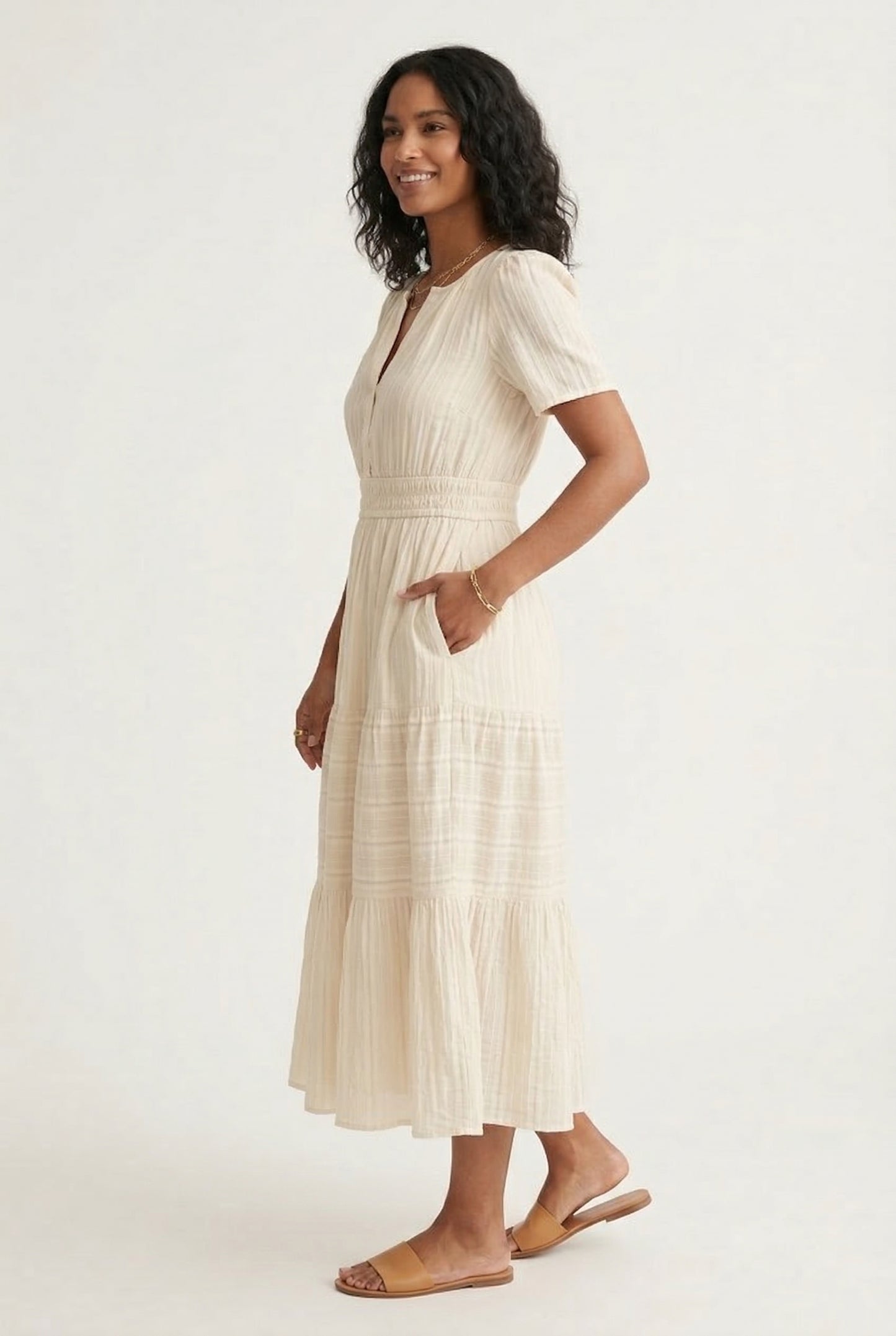 A woman posing in an Oat beige short-sleeve midi dress featuring a button-down bodice and flowy skirt.