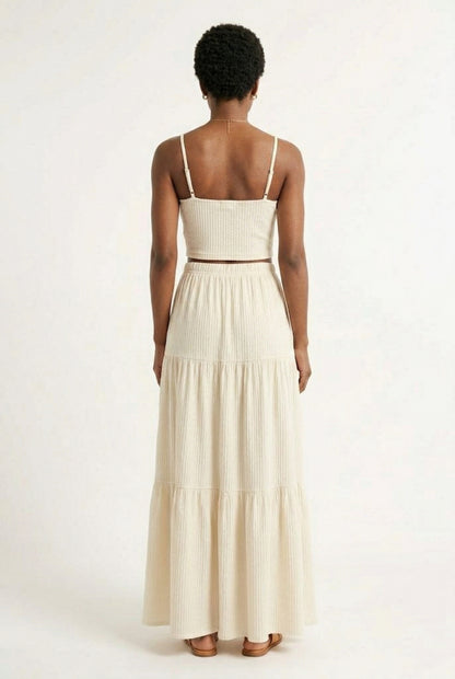 Woman modeling an Oat cream two-piece matching set featuring a spaghetti strap crop top and tiered maxi skirt