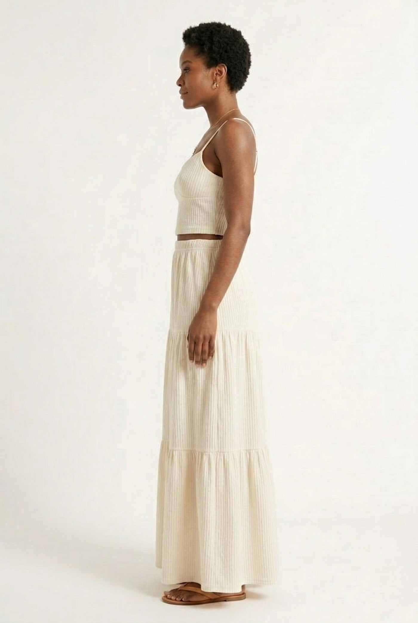 Woman modeling an Oat cream two-piece matching set featuring a spaghetti strap crop top and tiered maxi skirt