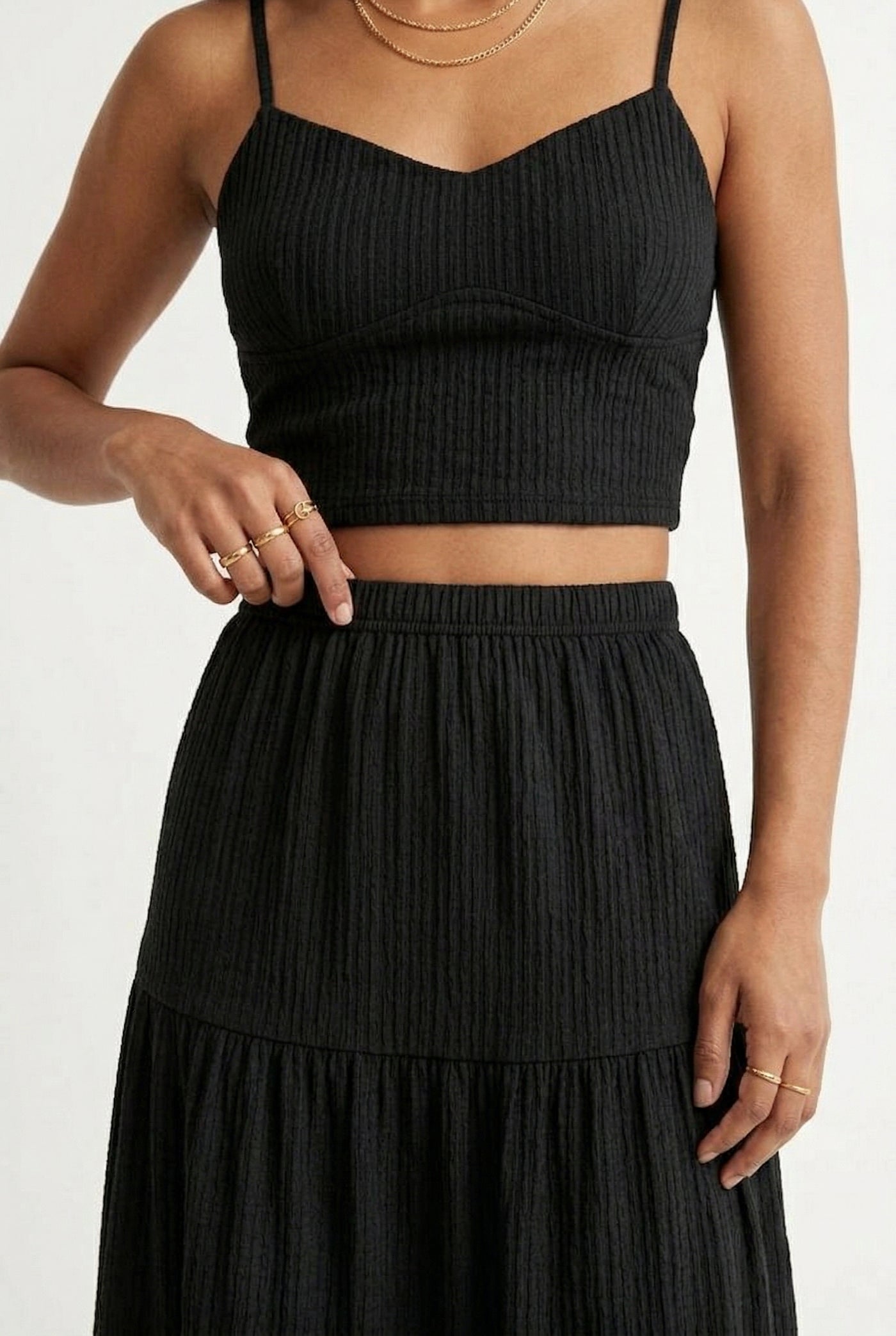 Woman modeling an Obsidian black two-piece matching set featuring a spaghetti strap crop top and tiered maxi skirt