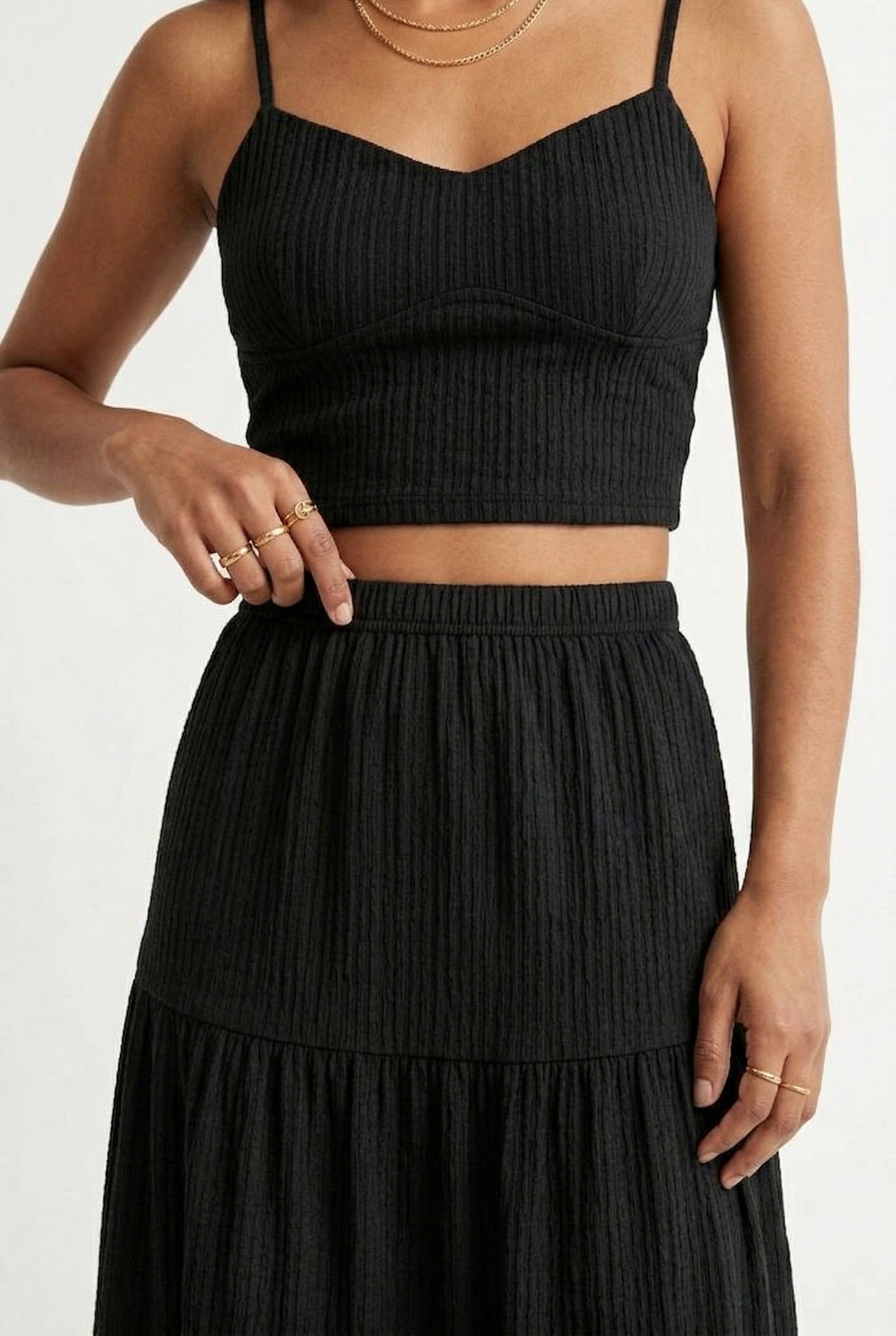 Woman modeling an Obsidian black two-piece matching set featuring a spaghetti strap crop top and tiered maxi skirt