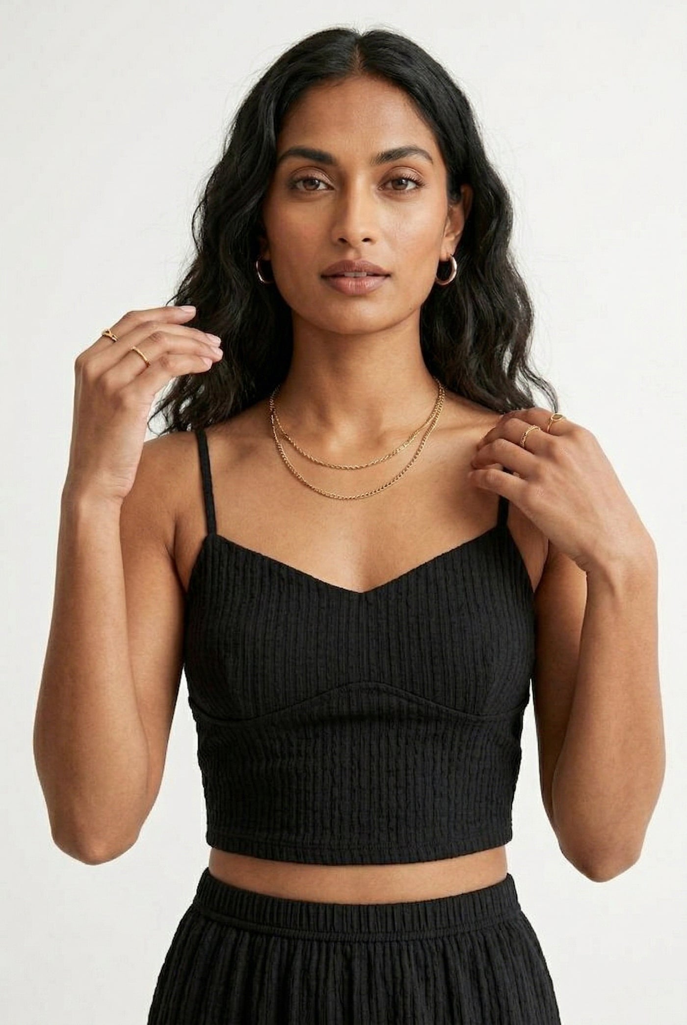 Woman modeling an Obsidian black two-piece matching set featuring a spaghetti strap crop top and tiered maxi skirt