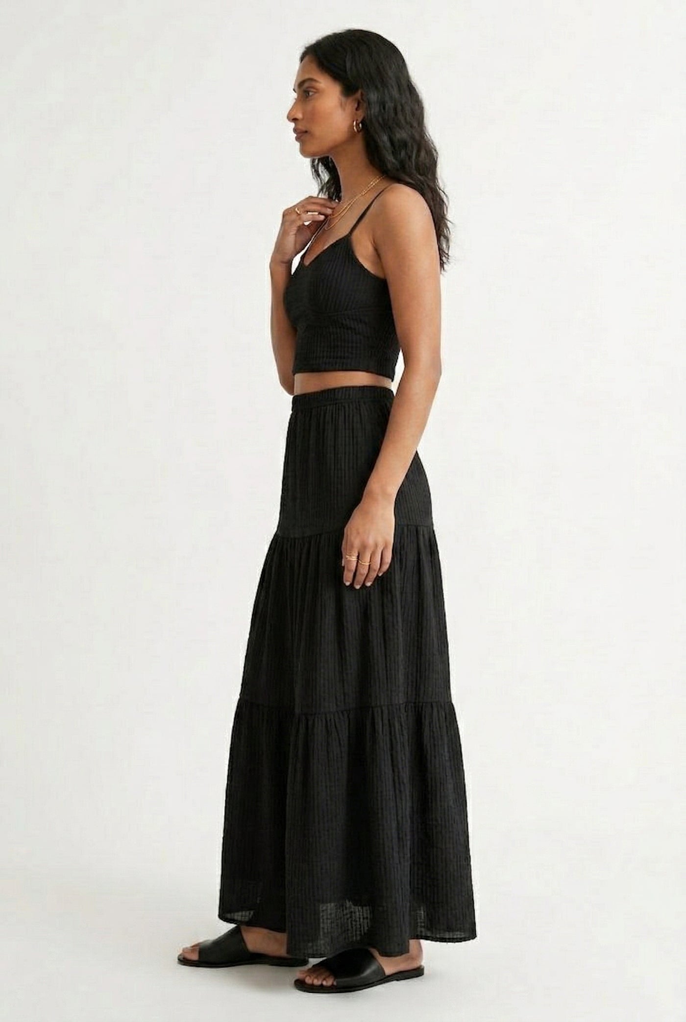 Woman modeling an Obsidian black two-piece matching set featuring a spaghetti strap crop top and tiered maxi skirt