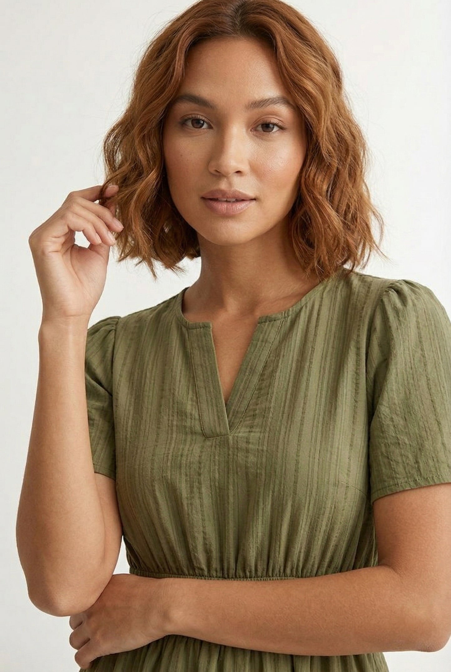 Woman wearing a short sleeve v-neck tiered dress in dark olive green