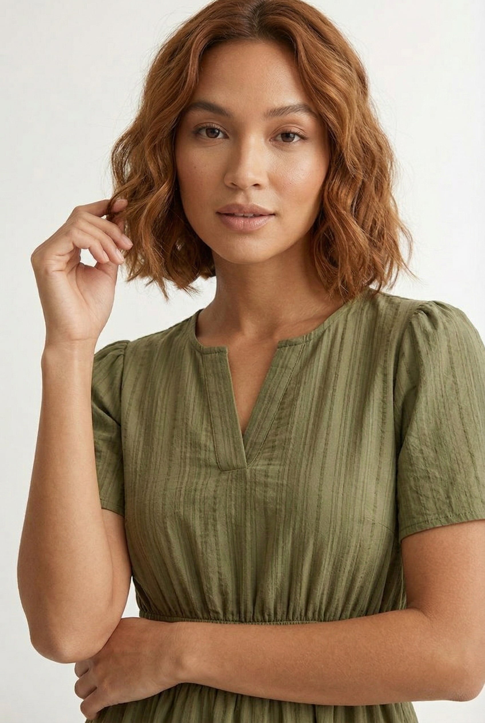 Woman wearing a short sleeve v-neck tiered dress in dark olive green