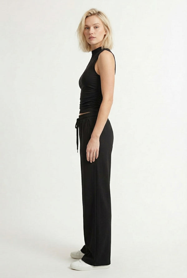 Woman wearing a classic onyx black sleeveless jumpsuit with a wide-leg silhouette.